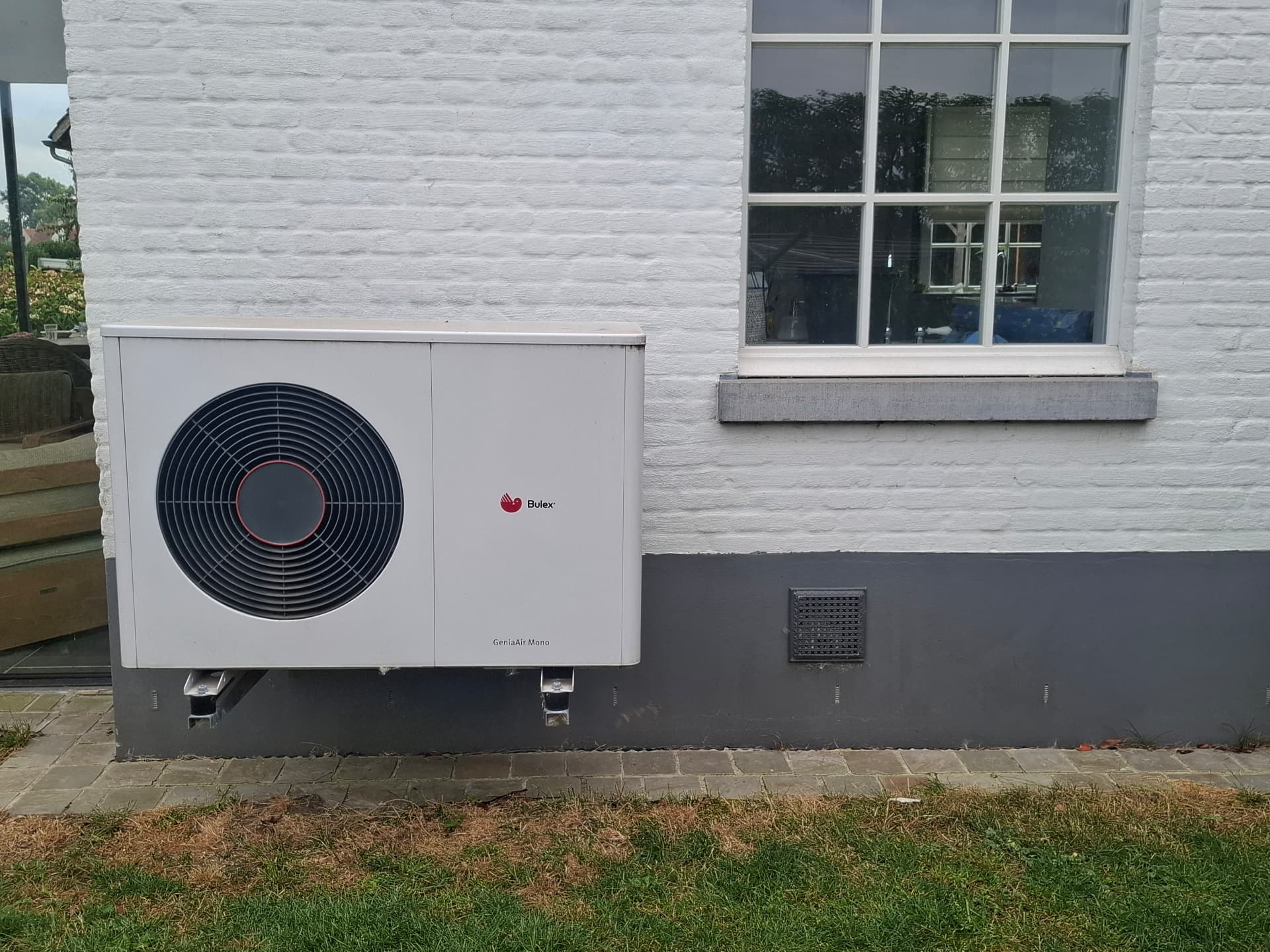 Monobloc hybride warmtepomp discreet geplaatst tegen gevel van woning in Kruisem